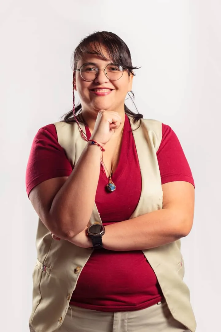 Edmary Mora, médica psiquiatra, sonríe con la mano bajo el mentón; lleva lentes, blusa vino y chaleco beige.