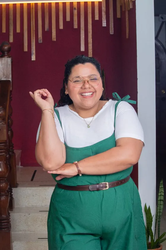 Luz Contreras, psicóloga, se ríe con un gesto de "todo bien" frente a la pared vino de Oikos.